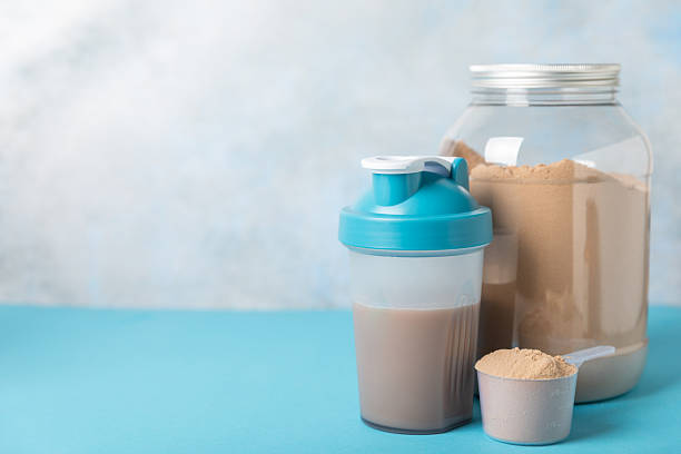istock Protein shake with protein powder on a colored background. The powder is mixed with water or milk. A dietary supplement for a balanced diet. Whey protein. Fitness and gym diet nutrition. 2243242241