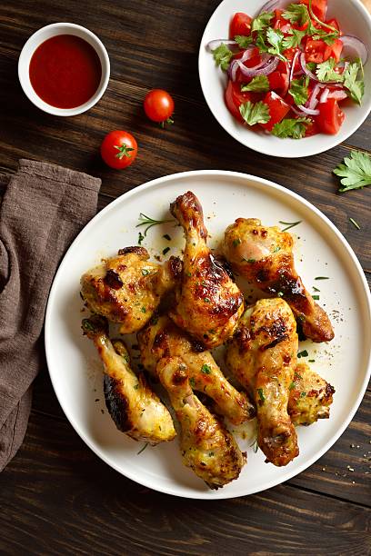 istock Roasted chicken drumsticks served with sauce and salad 2243243154