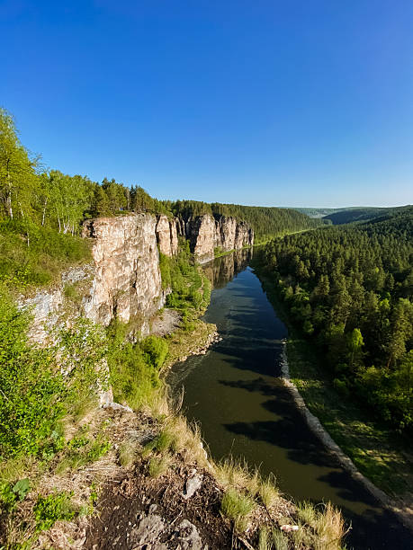 istock A tranquil river gracefully flows through a picturesque valley, which is surrounded by tall, majestic trees and sturdy rocks, creating a stunning and captivating natural landscape 2243243590
