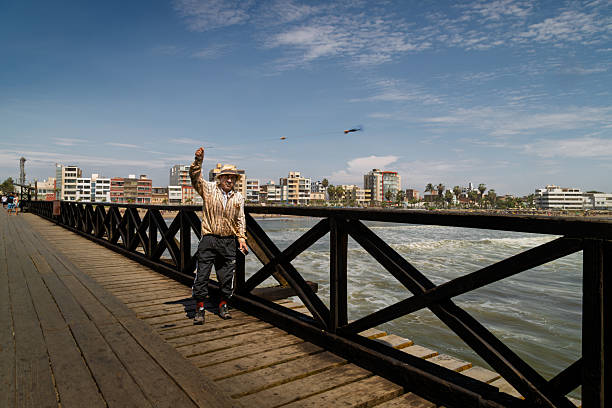 Pimentel, Peru – January 8, 2024: Fisherman casting a hook and lure with a cord from the pier