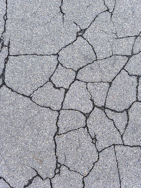 istock Close-up of cracked asphalt surface, showing texture and damage details 2243258554