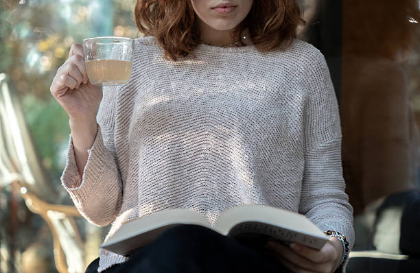 istock Woman holding a tea cup and reading a book 2243278233