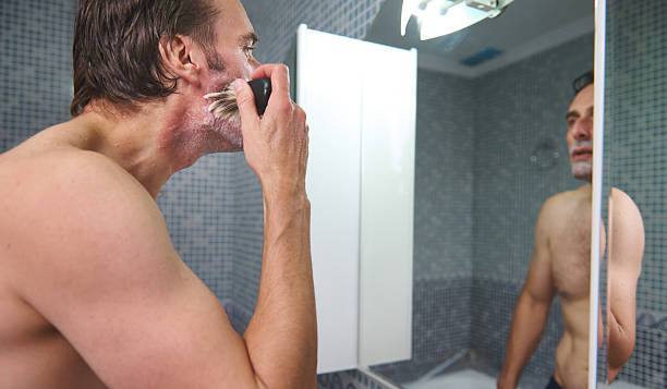 Man Shaving in Bathroom Mirror With Razor, Grooming, Personal Care, Morning Routine