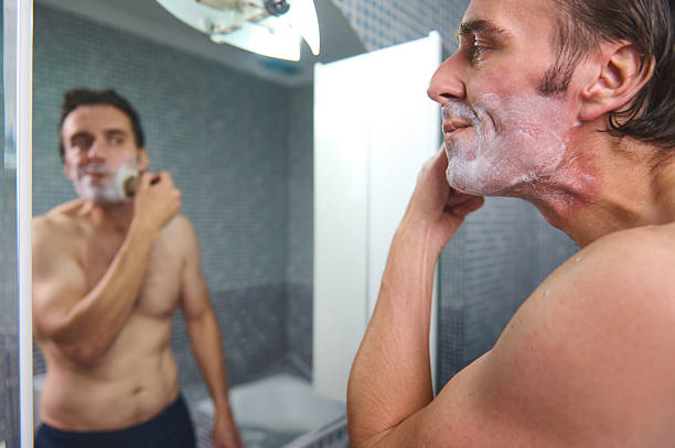 istock Man Shaving in Bathroom Mirror During Grooming Routine and Self-Care Moment 2243280047