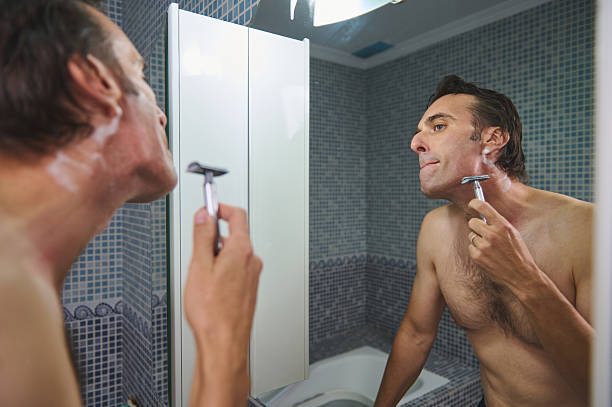 istock Man Shaving in Bathroom Mirror Reflection With Razor and Foam 2243281474