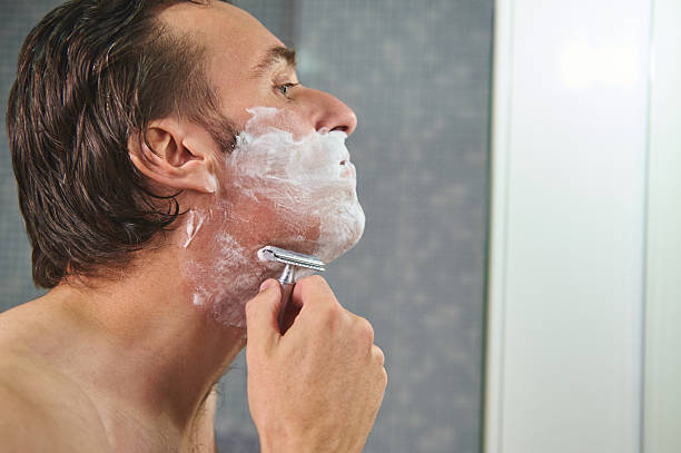 istock Man Shaving in Bathroom With Foam and Razor - Close Profile View 2243283141