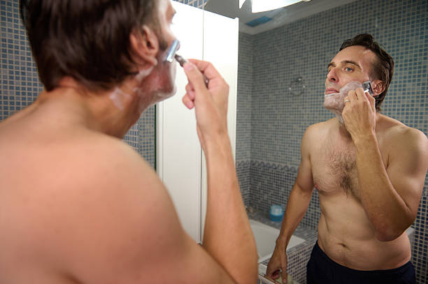 istock Man Shaving in Mirror at Home: Grooming Ritual in a Modern Bathroom Setting 2243283243