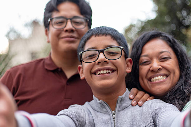 Hispanic mexican parents and son looking at camera smiling, taking a selfie