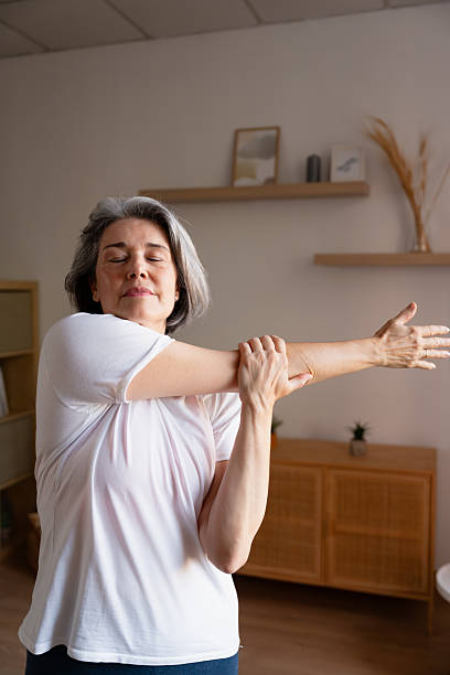 istock Senior woman doing arm stretching exercise at home 2243286478