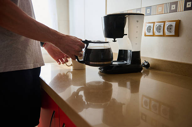 istock Cozy Kitchen Moment: Person Pouring Coffee From Drip Coffee Maker On Counter 2243286654
