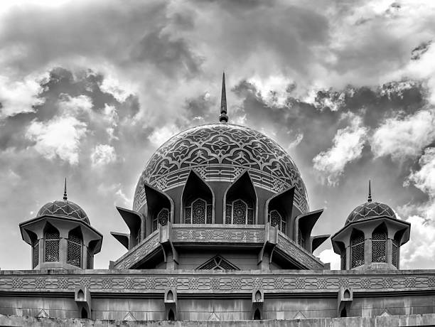 Putrajaya city lakeshore architecture landmarks in Malaysia - roof top of pink mosque dome under dramatic contrast sky.