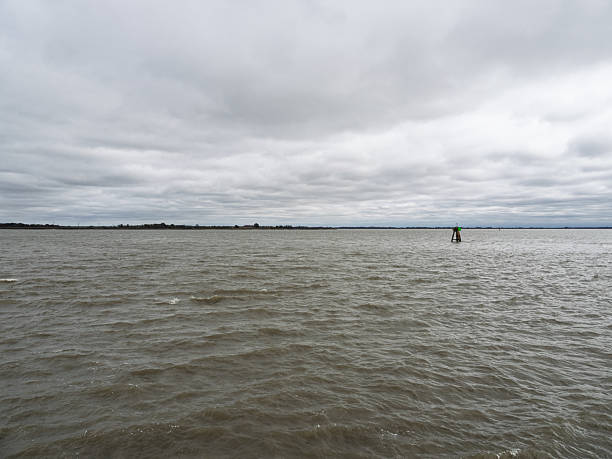Vast gray water of the Delaware River with a single navigation buoy