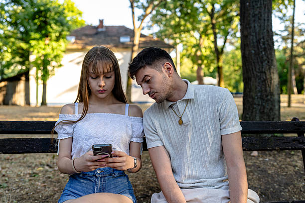 istock Couple sharing a moment on a park bench with a mobile phone 2243293260