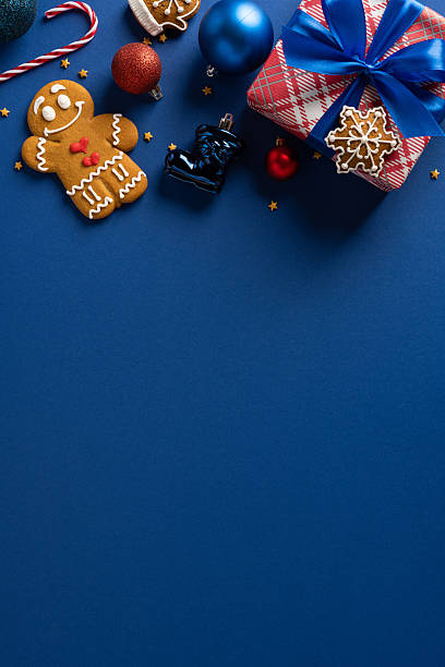 istock A festive vertical scene featuring a wrapped gift, gingerbread cookie, candy canes, and decorative ornaments set on a deep blue backdrop, ideal for Christmas and New Year greetings and holiday decor 2243294874