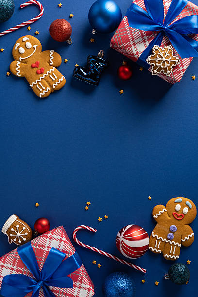 A vertical bright holiday scene featuring wrapped gifts, gingerbread cookies, candy canes, ornaments and glittering accents on a blue background