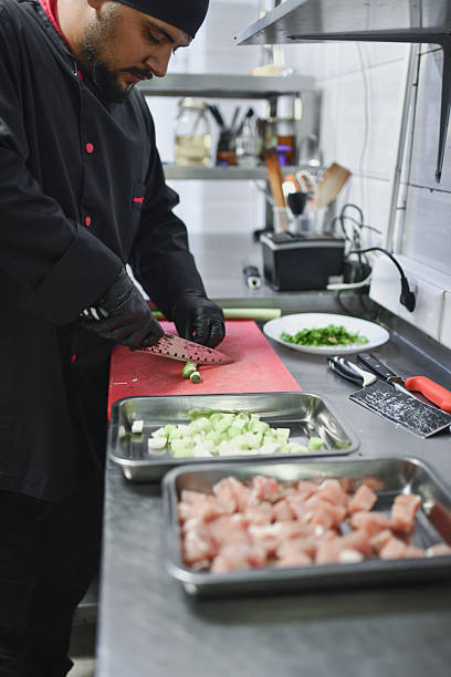 istock Professional Chef Chopping Vegetables and Prepping Chicken in a Modern Kitchen Studio 2243295989