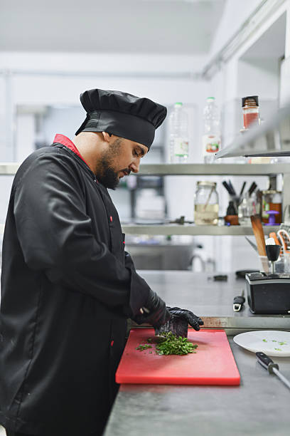 istock Professional Chef Chopping Fresh Herbs On Red Cutting Board In Busy Kitchen 2243296004
