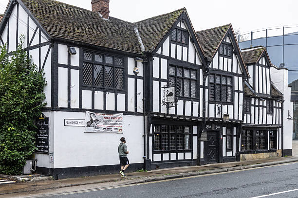 The Black Swan Pub, a Grade II Listed Building on Peasholme, central York, England. Originally a house, it was constructed in the late 16th century, with later additions. A pedestrian is walking past. A Cat from the York Cat Trail is above the door of the pub.
