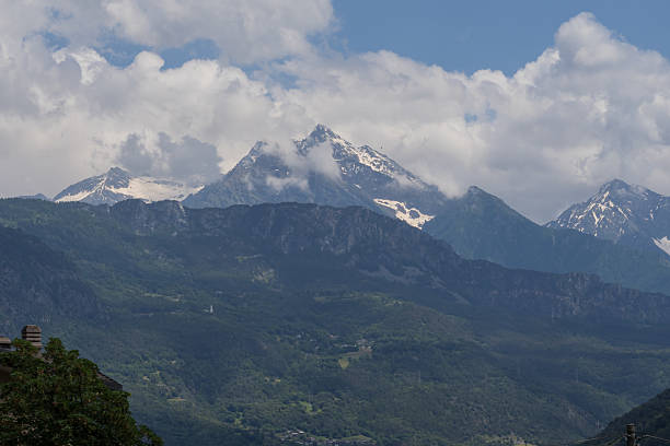istock Snow capped mountain peaks above forest slopes and clouds 2243297391
