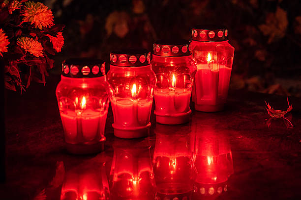 Grave candles burning brightly in a cemetery at night, honoring the memory of loved ones