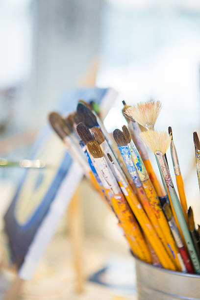 istock Art brushes placed in containers inside an art classroom with warm daylight. Creative education, painting supplies and artistic lifestyle concept for students and artists. 2243300900