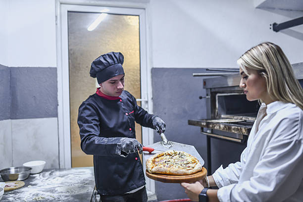 Pizza Chef (Pizzaiolo) Making Pizza in Outdoor Brick Oven Kitchen on a Sunny Day