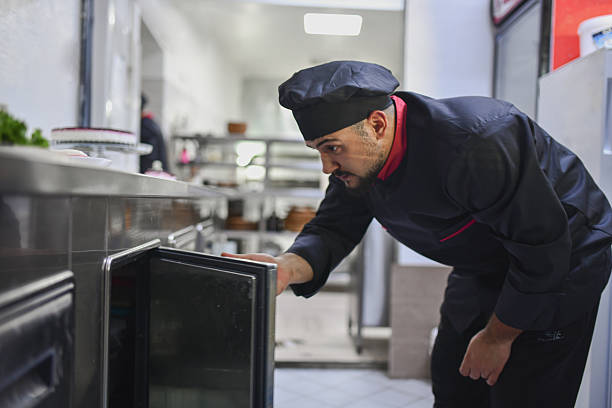Professional Chef Checking the Kitchen Storage for Fresh Ingredients in Busy Commercial Kitchen