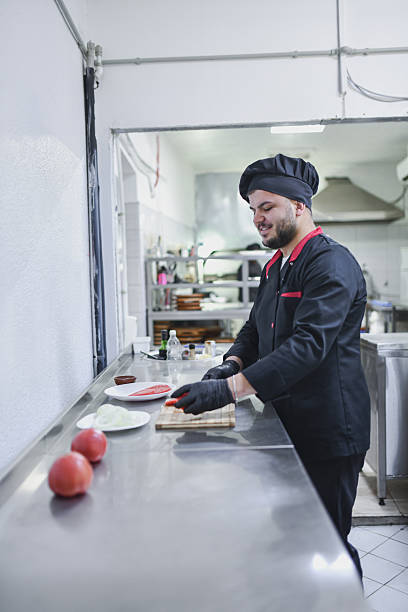 istock Chef Prepares Fresh Tomatoes On Cutting Board In Stainless Steel Kitchen Studio 2243302661