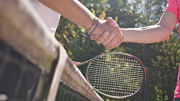 istock Two Individuals Shaking Hands over a Tennis Net on a Sunny Day 2243310787