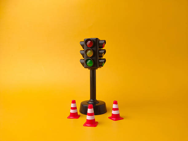 istock The image shows a miniature traffic light and three miniature traffic cones on a yellow background 2243313603