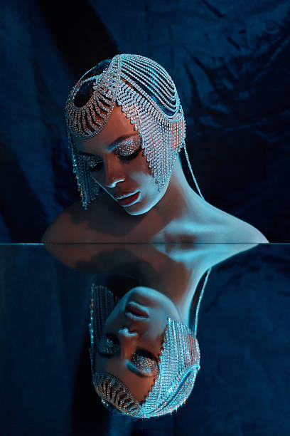 istock mannequin adorned with a stunning beaded headpiece sits in a darkened space, its reflection beautifully captured in a calm water surface, creating an artistic composition 2243317610