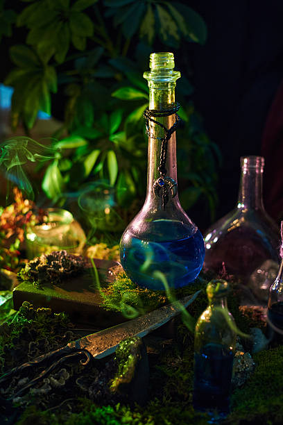 istock Brightly colored potion bottles sit among green plants and stones in a dimly lit space. Smoke swirls around, creating a magical atmosphere, perfect for a fantasy setting 2243317639