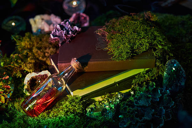 istock dark surface features two stacked books topped with colorful moss and crystals, alongside a small bottle filled with a red liquid. setting evokes a sense of fantasy 2243317641