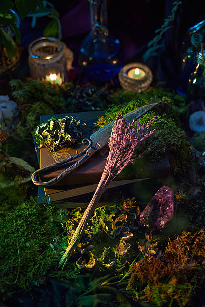 istock detailed scene shows an altar surrounded by moss, candles, and potion bottles. Scissors and dried herbs lie atop ancient books, creating a magical atmosphere at dusk 2243317644