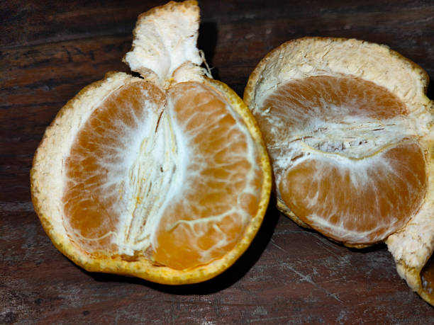istock an orange cut into two parts on a wooden table 2243320082