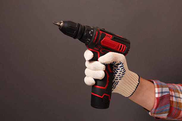 istock Handyman holding electric screwdriver on brown background, closeup 2243327732