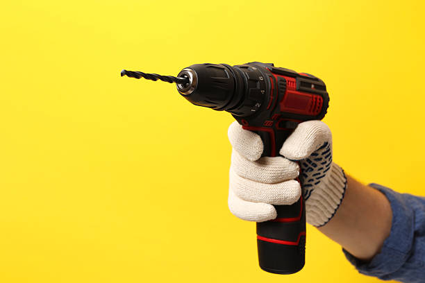 istock Handyman holding electric screwdriver on yellow background, closeup 2243327741