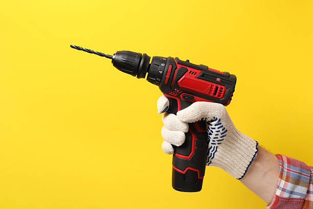 istock Handyman holding electric screwdriver on yellow background, closeup 2243327791
