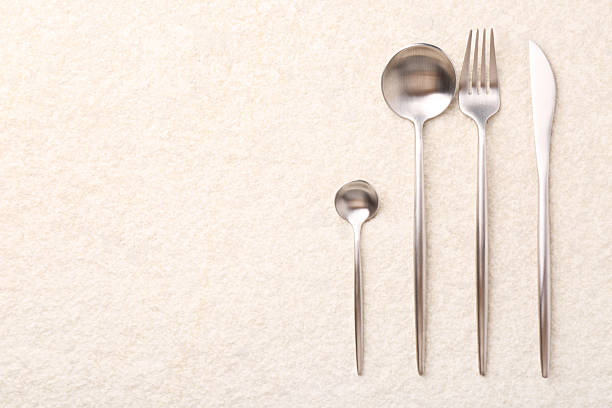 Stylish silver cutlery set on light textured table, flat lay. Space for text