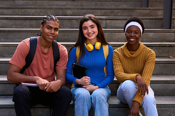 istock Diverse students sitting on campus stairs smiling 2243337690