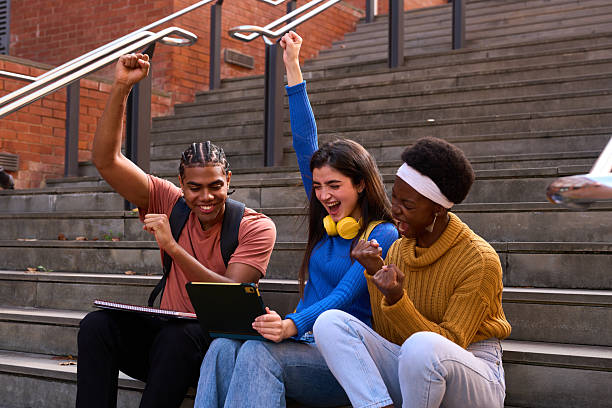 Excited students running towards camera on college campus