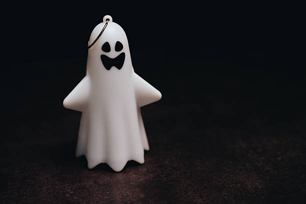 istock Cute Ghost Keychain for Halloween Decoration and Accessories with a Friendly Face on a Dark Background 2243338287