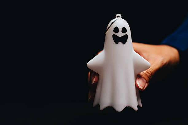 istock Cute White Ghost Toy Held by Hand with Black Background, Perfect for Halloween Decorations and Festive Imagery 2243338297