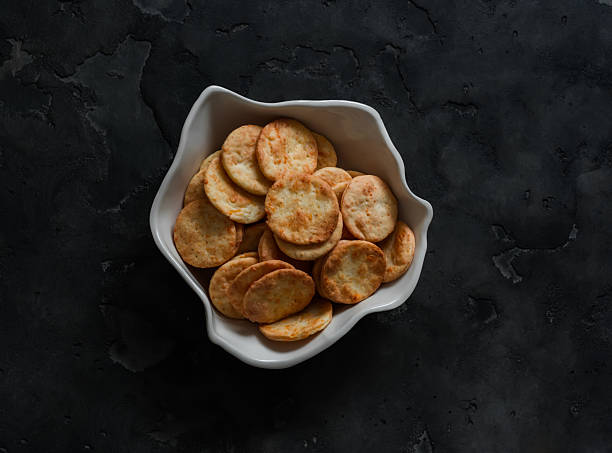 istock Cheddar cheese cracker in a ceramic bowl on a dark background, top view 2243340311