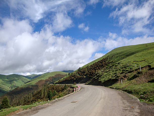 istock Scenic winding road through green mountainous area under blue sky 2243343219