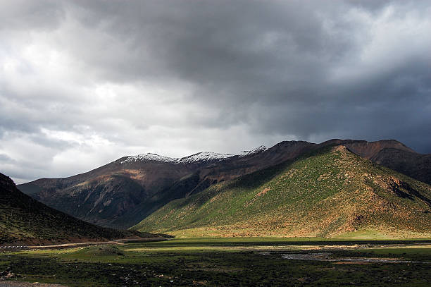 A stunning view of a mountain range with green valleys under a stormy sky, showcasing natural landscape beauty.