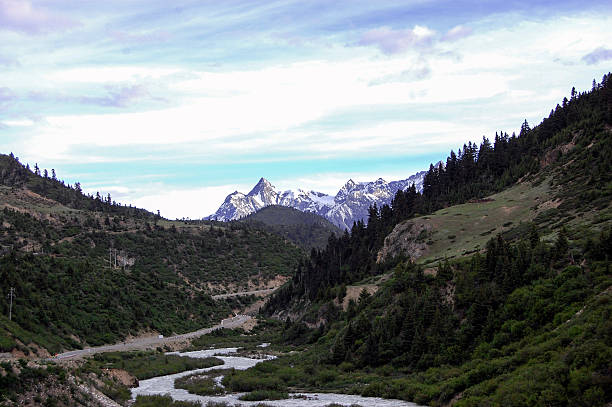 istock Scenic mountain valley with river and snow-capped peaks under a cloudy sky 2243343410