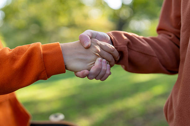 istock Two people engage in a handshake outdoors in a park during a sunny afternoon showing unity and friendship 2243350925