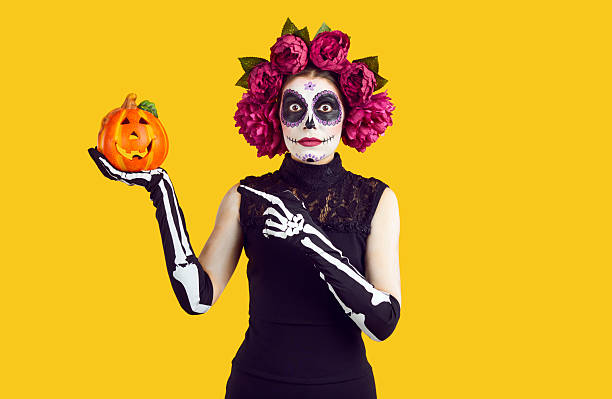 istock Amazed woman with creative Halloween face art with surprised expression showing decorative pumpkin. 2243352483