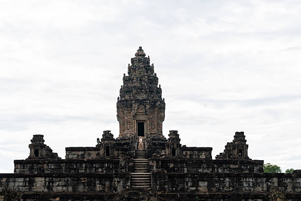 Woman standing on stone stairs, exploring the ancient baphuon temple in angkor thom